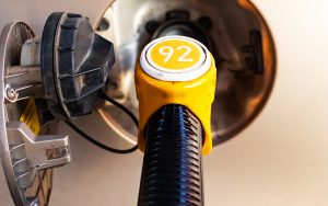 Fuel pump inserted in the gas tank hatch. Refueling a passenger car with gasoline. Yellow fuel pump with number 92 petrol , vertical closeup
